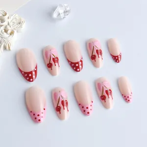 Almond press-on nails with red polka dots, cherry patterns, and pink bows on white background