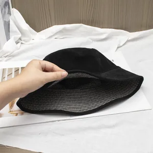 Detail shot of the double-sided black bucket hat with black and white plaid inner lining