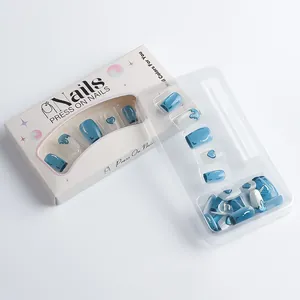Detail of blue cat-eye press-on nails with heart patterns in white packaging box
