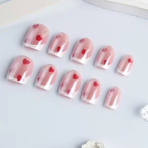 Short square press-on nails with pink base, heart patterns and French white tip design