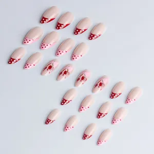 French tip press-on nails with red polka dots, cherry patterns, and pink bows
