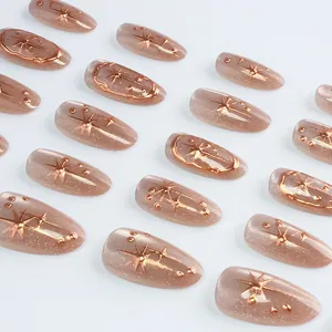 Detail of almond cat-eye press-on nails with rose gold star relief and glitter accents