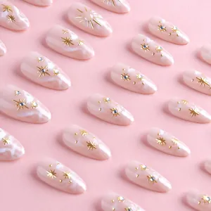Detail of pink marble press-on nails with golden star patterns and micro rhinestones