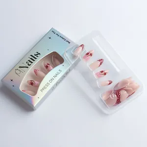 Detailed view of press-on nails set with red cherry and bow designs in laser packaging