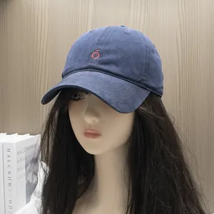 Detail view of a navy blue washed cotton baseball cap with red embroidered apple logo