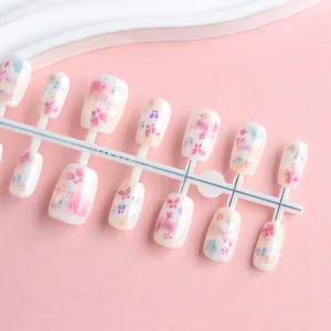 Detail view of short square press-on nails with sweet purple floral patterns and glitter finish