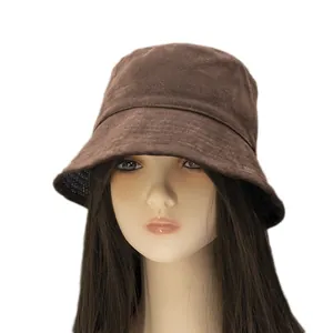 Brown suede bucket hat with plaid lining and decorative stitching on a model