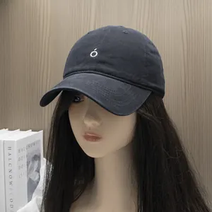 Detail of black cotton baseball cap featuring white 'ó' embroidery on a mannequin