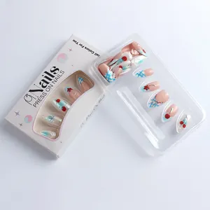 Detail of almond press-on nails featuring cherry patterns and silver 3D bow accents