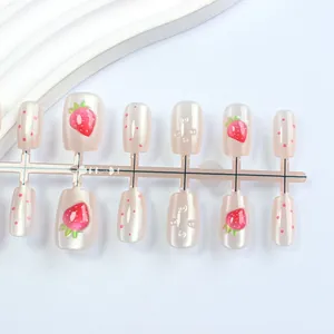 Detail of pink cat eye press-on nails with strawberry art and 3D water droplet texture