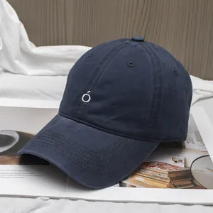 Detail of navy blue cotton baseball cap featuring minimalist white embroidered logo