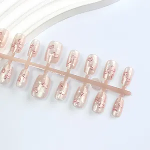 Nahaufnahme kurzer Trapez-Nagelspitzen mit roségoldenen Herzen und Sternen-Akzenten