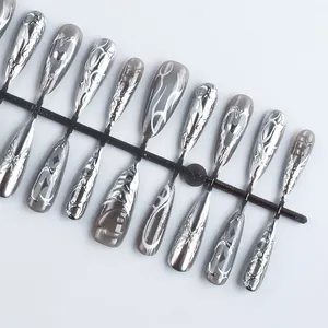 Macro detail of chrome silver press-on nails with 3D embossed heart and floral patterns