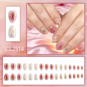 Short oval press-on nails with 3D gold bow and heart charms on pink gradient base