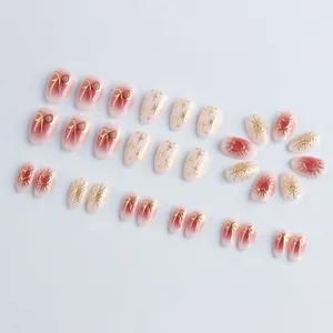Short oval press-on nails with 3D gold bow and heart accents on pink gradient base