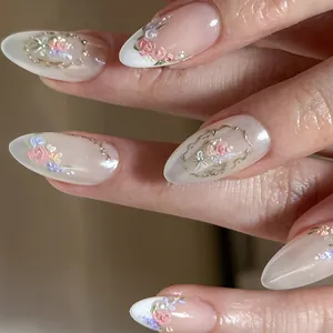 Macro shot of almond-shaped press-on nails with 3D floral reliefs and gold baroque accents