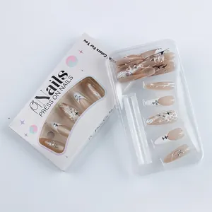 Detail showing elegant French press-on nails with glitter and cross art in a white box