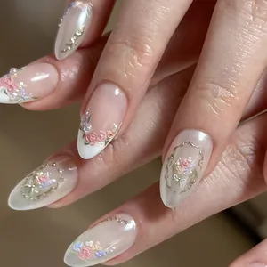 Macro detail of 3D floral embossing and pearls on elegant French almond false nails