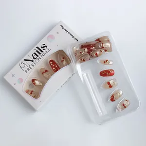 Detail of red cherry press-on nails with golden edges in white branded packaging