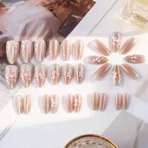 Detail of almond cat eye press-on nails with 3D floral motifs and gold glitter accents