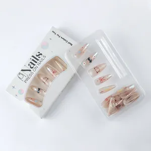 Macro view of long almond press-on nails with cute cat and floral patterns in packaging