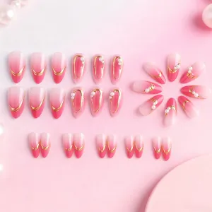 Detail of almond pink gradient press-on nails with gold edges and micro pearls