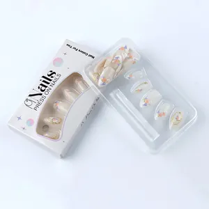Detail of floral press-on nails with 3D gold accents and pearls in retail box