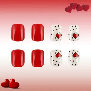 Detail view of short square press-on nails with red glossy finish and heart polka dot patterns