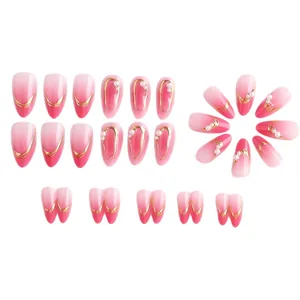 Pink gradient almond press-on nails with gold lines and pearl accents on white backdrop