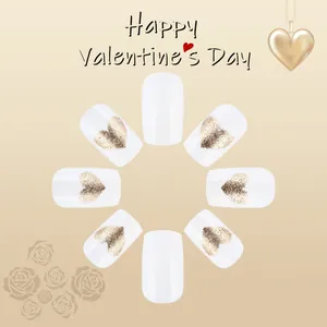 Close-up of white glossy press-on nails with golden glitter heart patterns for Valentines Day
