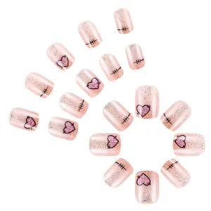 Kurze künstliche Nägel in Rosa mit Glitzer, Herzmuster und schwarzen Nahtdetails