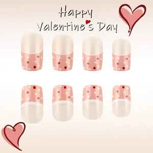 Dettaglio unghie finte di San Valentino rosa e beige con motivo a pois e cuore rosso