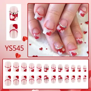 Short glossy press-on nails with red hearts, pearls, and rhinestones set on white base