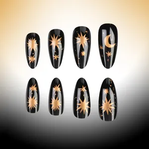 Detailed view of long almond press-on nails in glossy black with gold star and moon patterns