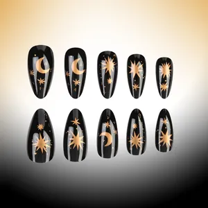 Macro detail of black almond press-on nails featuring golden moon and star celestial designs