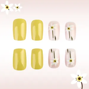 Detail of yellow glossy press-on nails with white daisy floral patterns on pink base