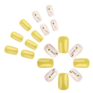 Glossy yellow press-on nails with white daisy floral design on square artificial nails
