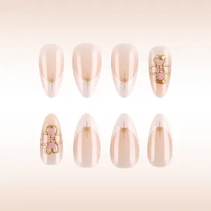 Detail of almond-shaped press-on nails with 3D pink flowers and gold French tips