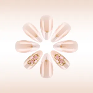 Almond shaped press-on nails with nude pink base, gold V-french tips and 3D floral accents
