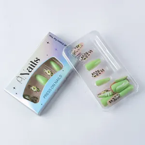 Detail of green floral press-on nails with long coffin shape in premium packaging