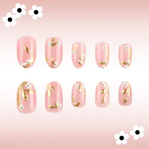 Detail of pink press-on nails with golden leaf relief and white floral patterns
