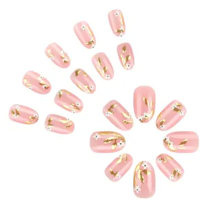Short oval pink press-on nails with gold leaf patterns and small white flowers