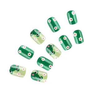 Detail of green press-on nails with cute frog and flower patterns and fine glitter