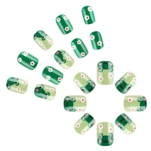 Detail of short round green press-on nails with cute frog and white flower patterns