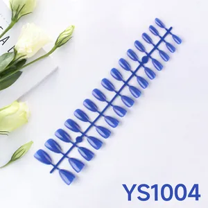Glossy royal blue almond press-on nails set displayed with floral props and magazine