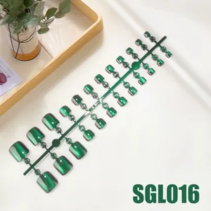 Detailed view of dark green cat eye press-on toenails on wood tray with greenery