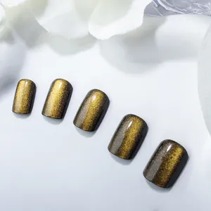 Close-up of brown cat-eye press-on nails with golden magnetic shimmer on white fabric