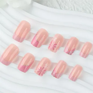 Detailed view of pink floral press-on nails with daisy patterns and glitter accents