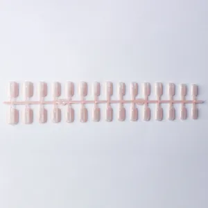 Détail de faux ongles carrés courts rose clair effet œil de chat et pailletés