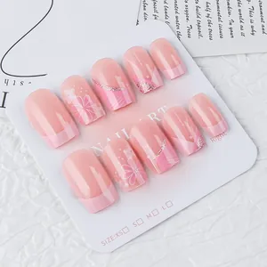 Detail view of pink glossy press-on nails with floral patterns and glitter on a card